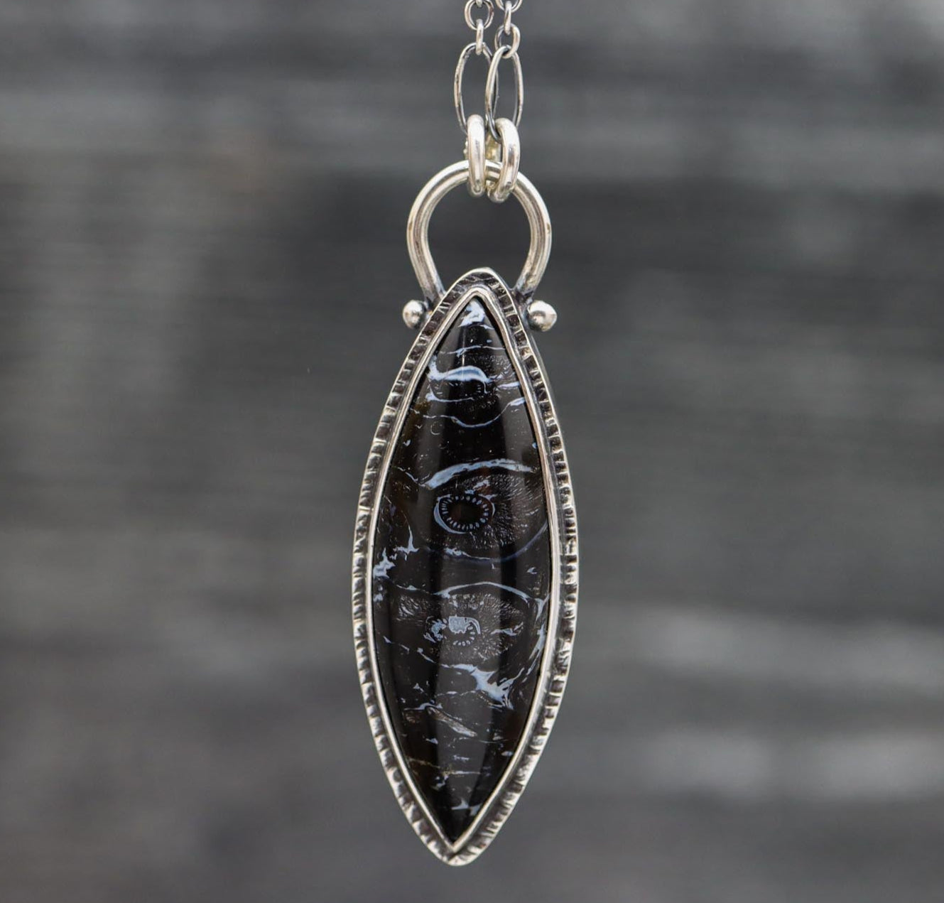 A sterling silver necklace featuring a petrified palm wood gemstone in a marquis shape with a double bezel setting, suspended from an oval-shaped chain.