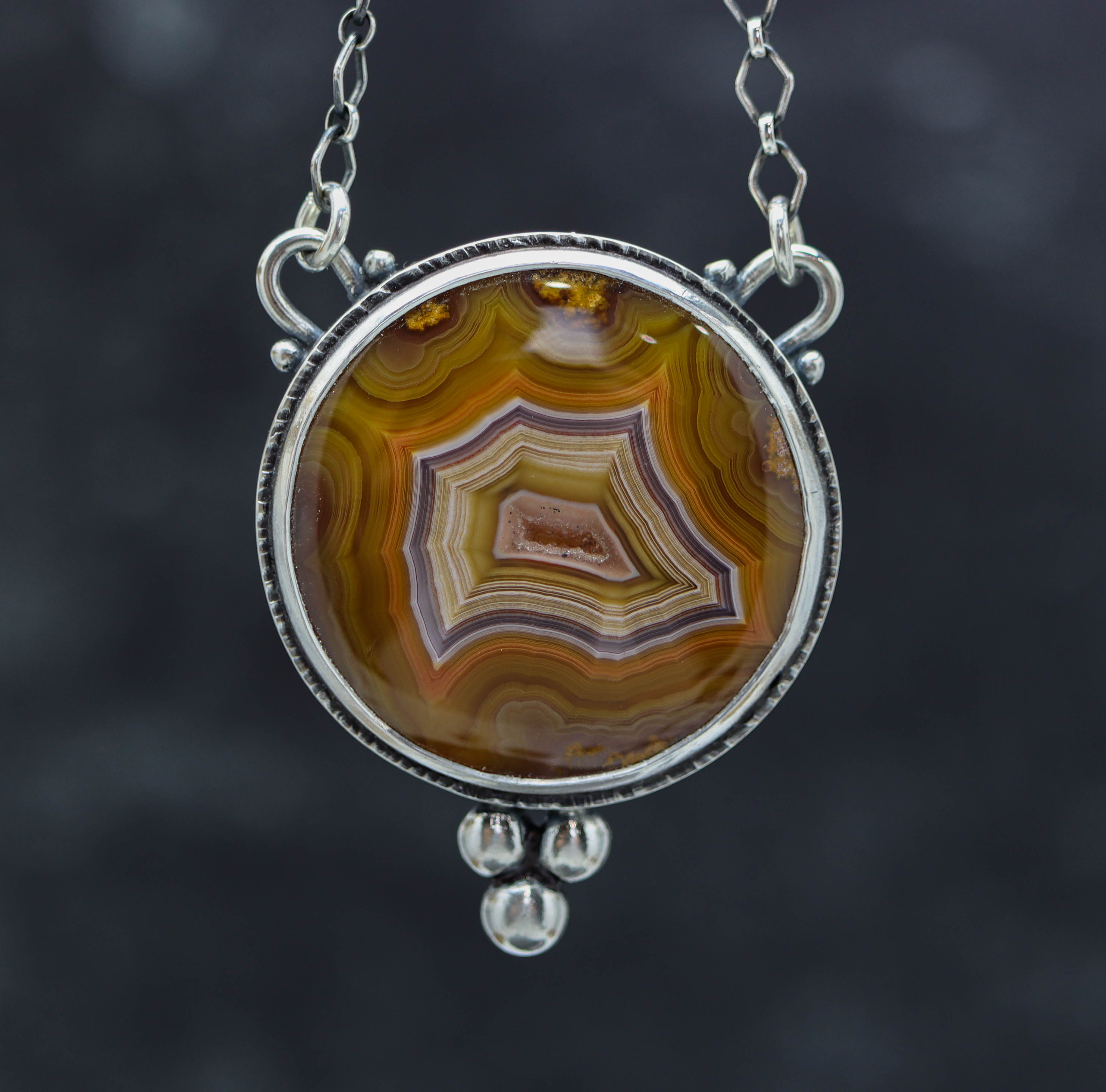 A sterling silver necklace featuring a large laguna agate stone with a window cut in the back to showcase the stone from both sides, completed with a lobster claw closure.