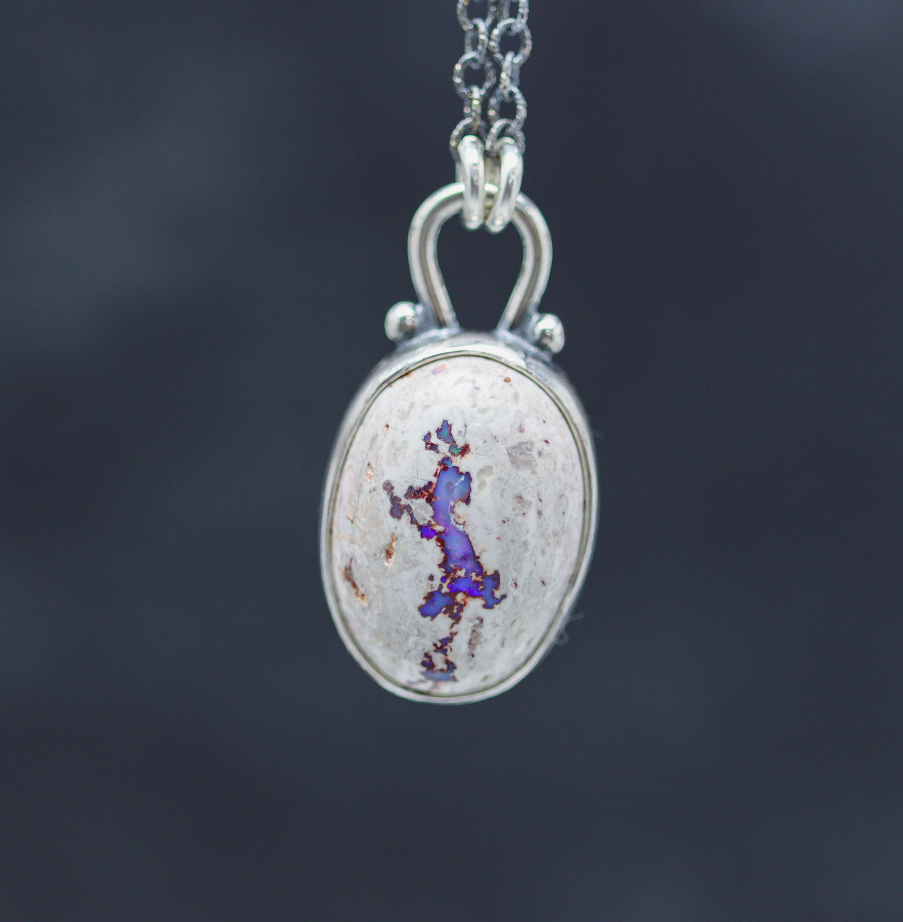 Silver pendant with a unique design on a dark background