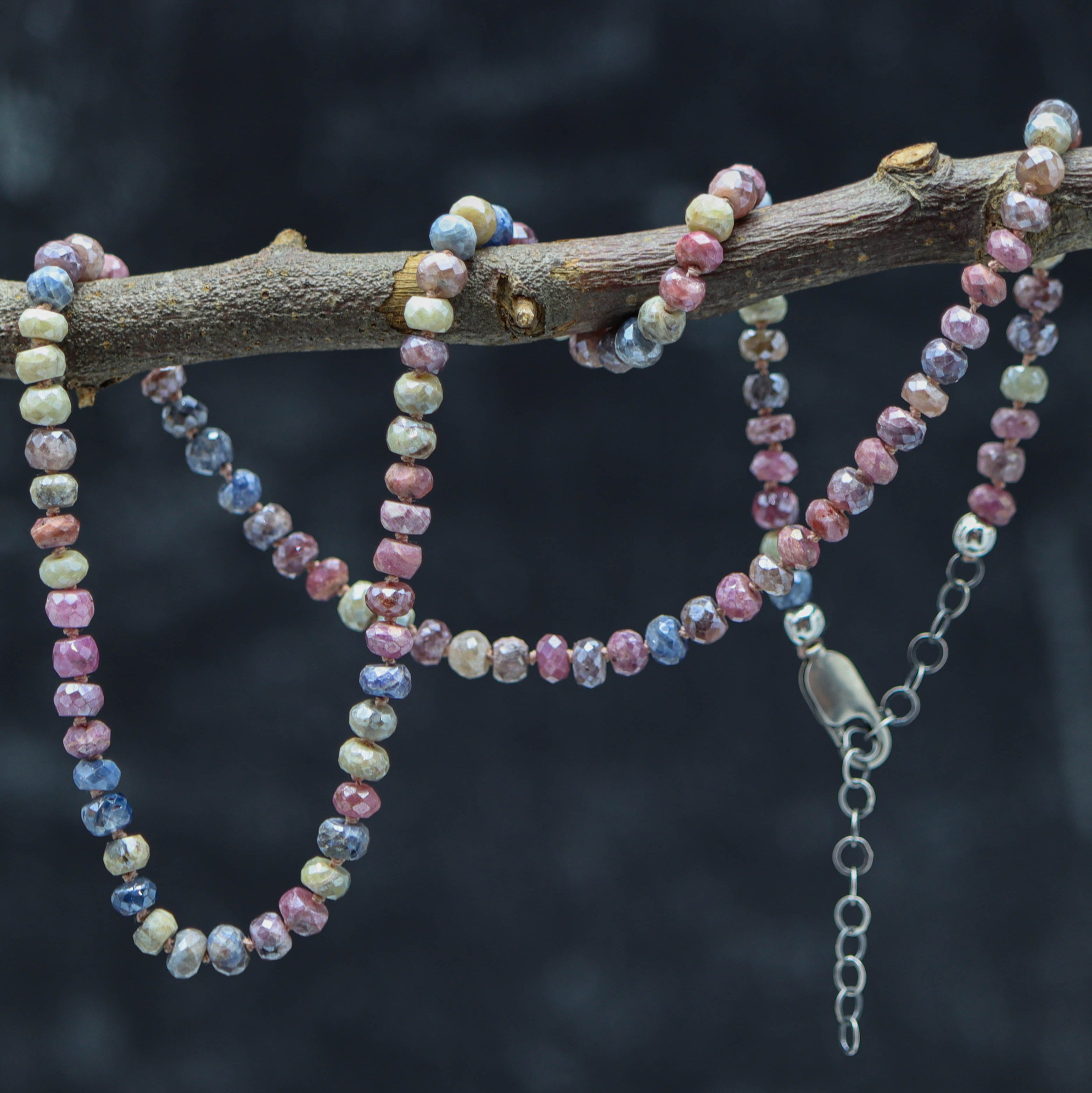 A sterling silver necklace with hand knotted multicolored sapphire beads, featuring a lobster claw closure.