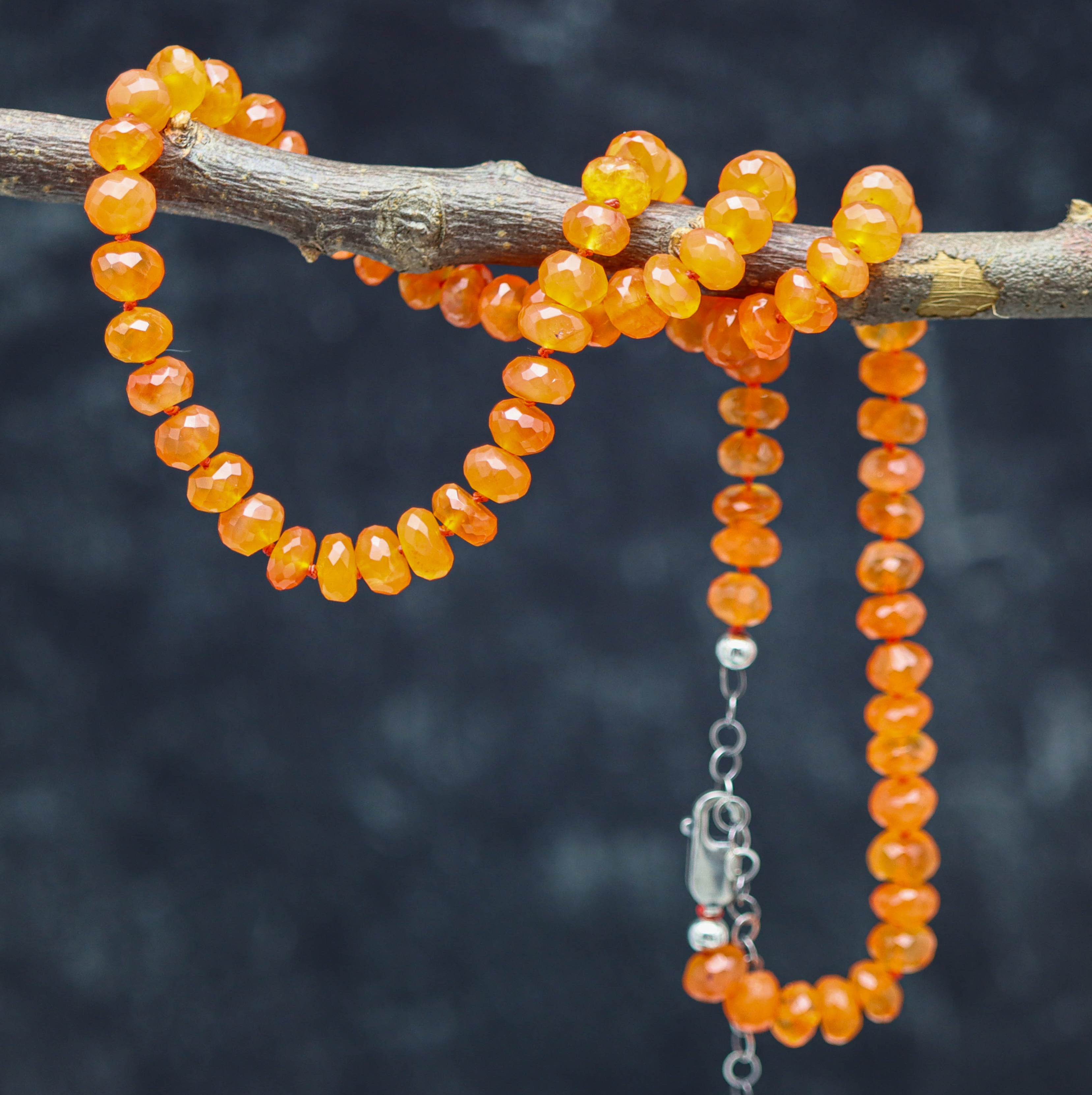 A hand knotted necklace with sterling silver closure featuring faceted roundel carnelian beads in a juicy tangerine orange color.