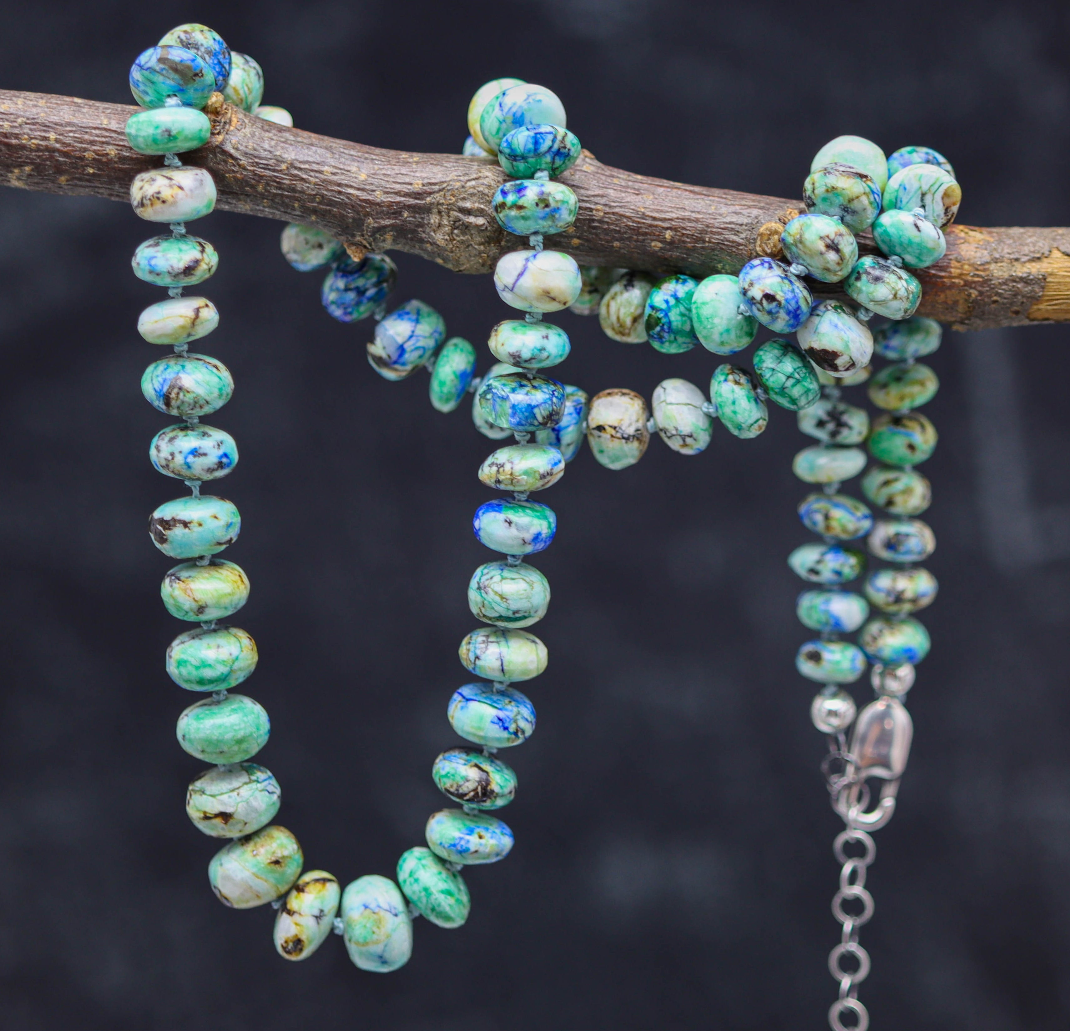 azurite malachite hand knotted necklace on a branch against a dark background