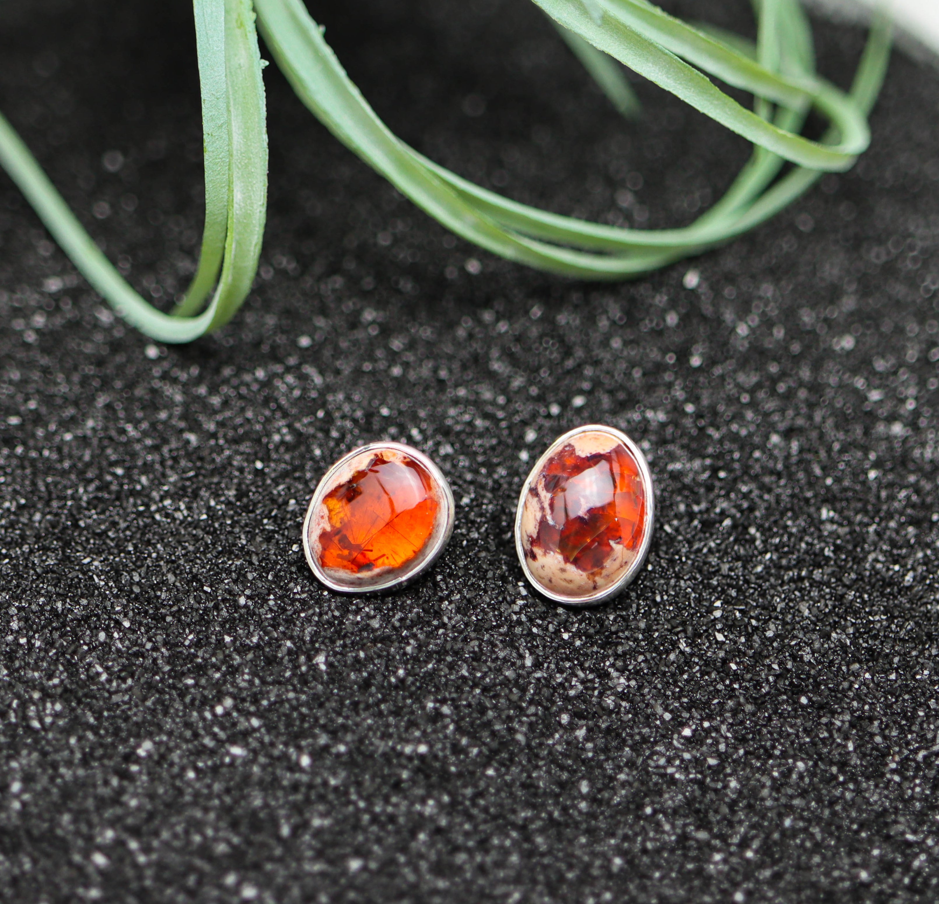 Pair of earrings with Mexican fire opal gemstones on a black surface