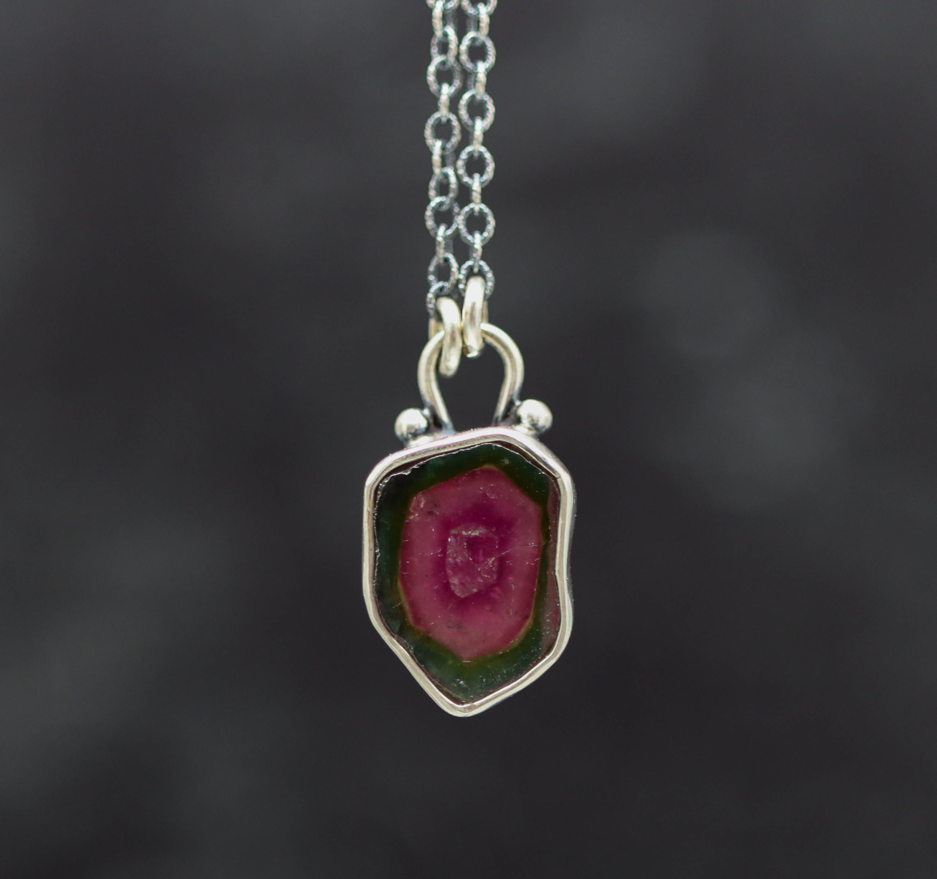 Necklace with a watermelon tourmaline pendant on a dark background
