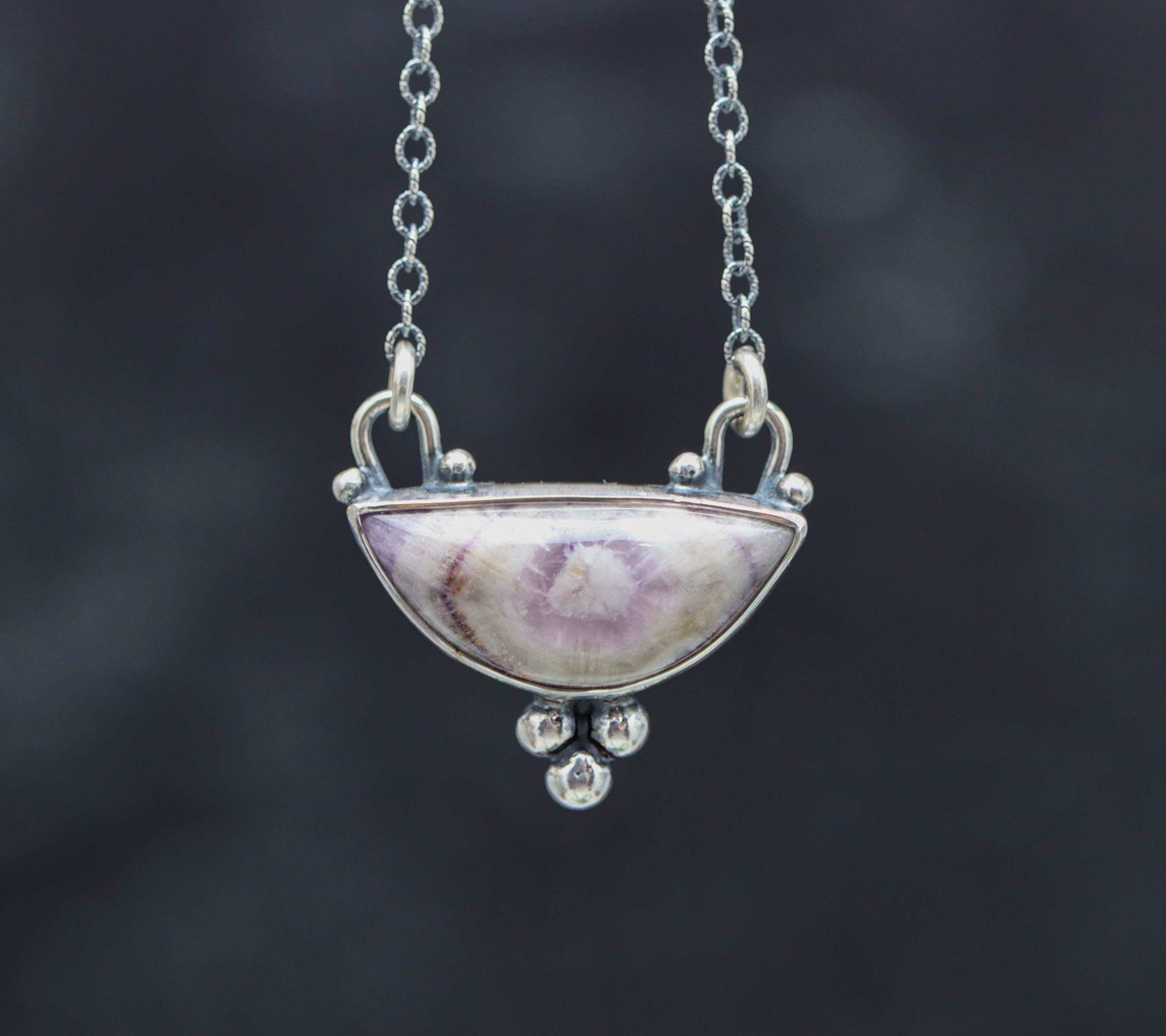 Silver necklace with a unique pendant on a dark background