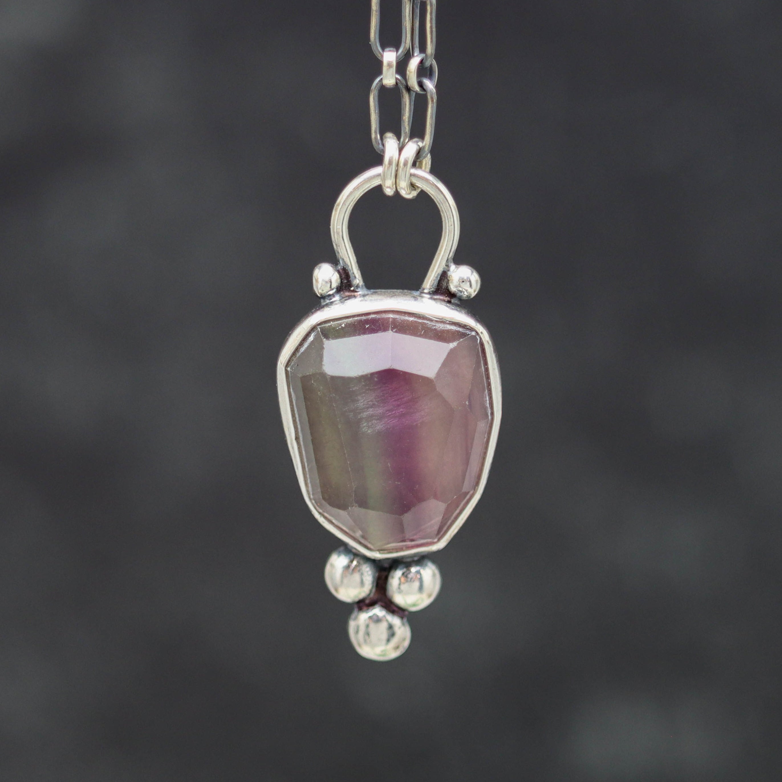 Silver pendant with a pink stone on a dark background