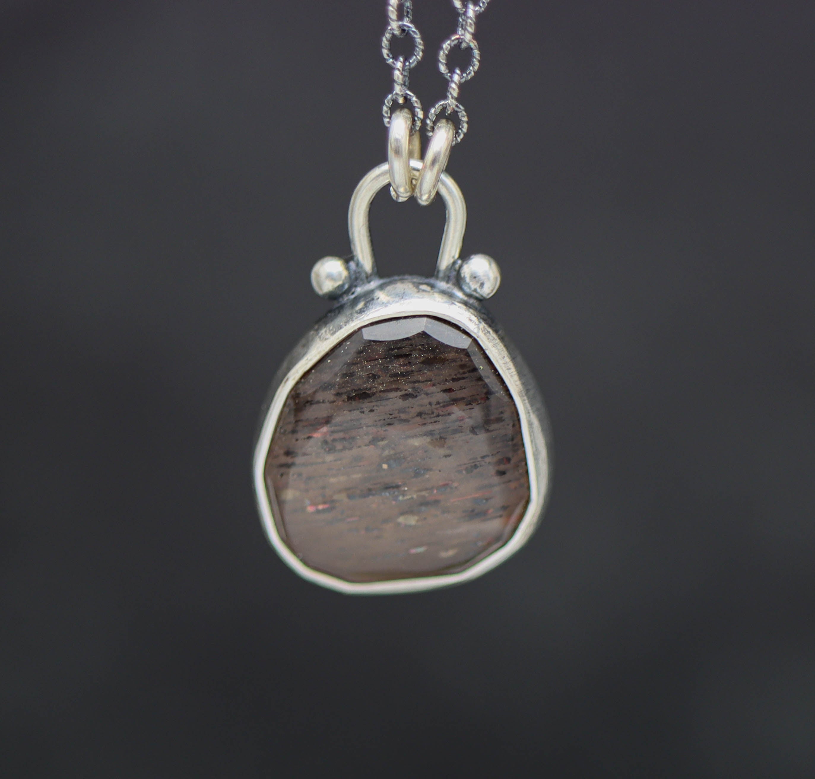 Silver pendant with a African Fire sun stone on a dark background