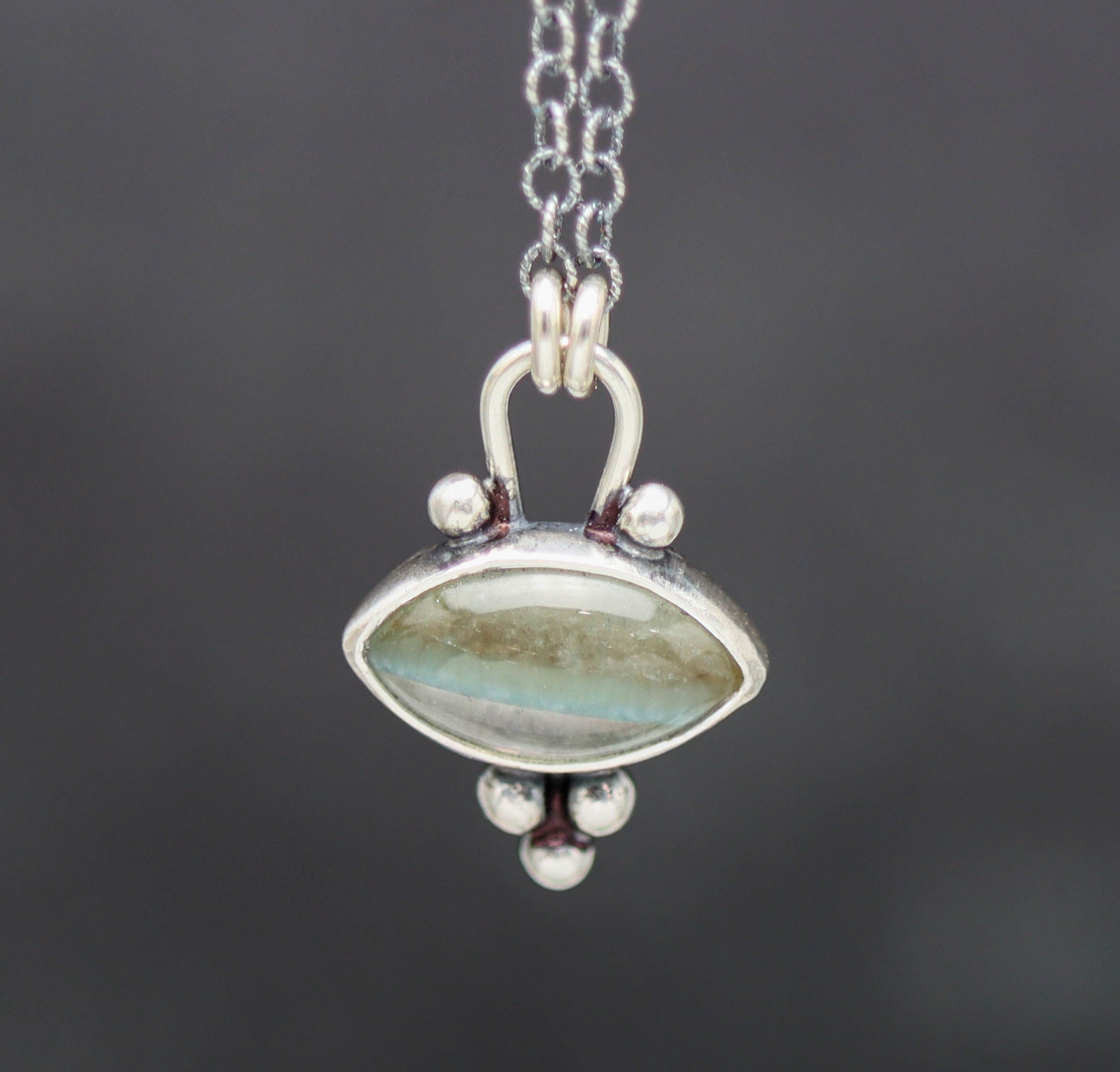 Silver pendant with a gemstone on a dark background