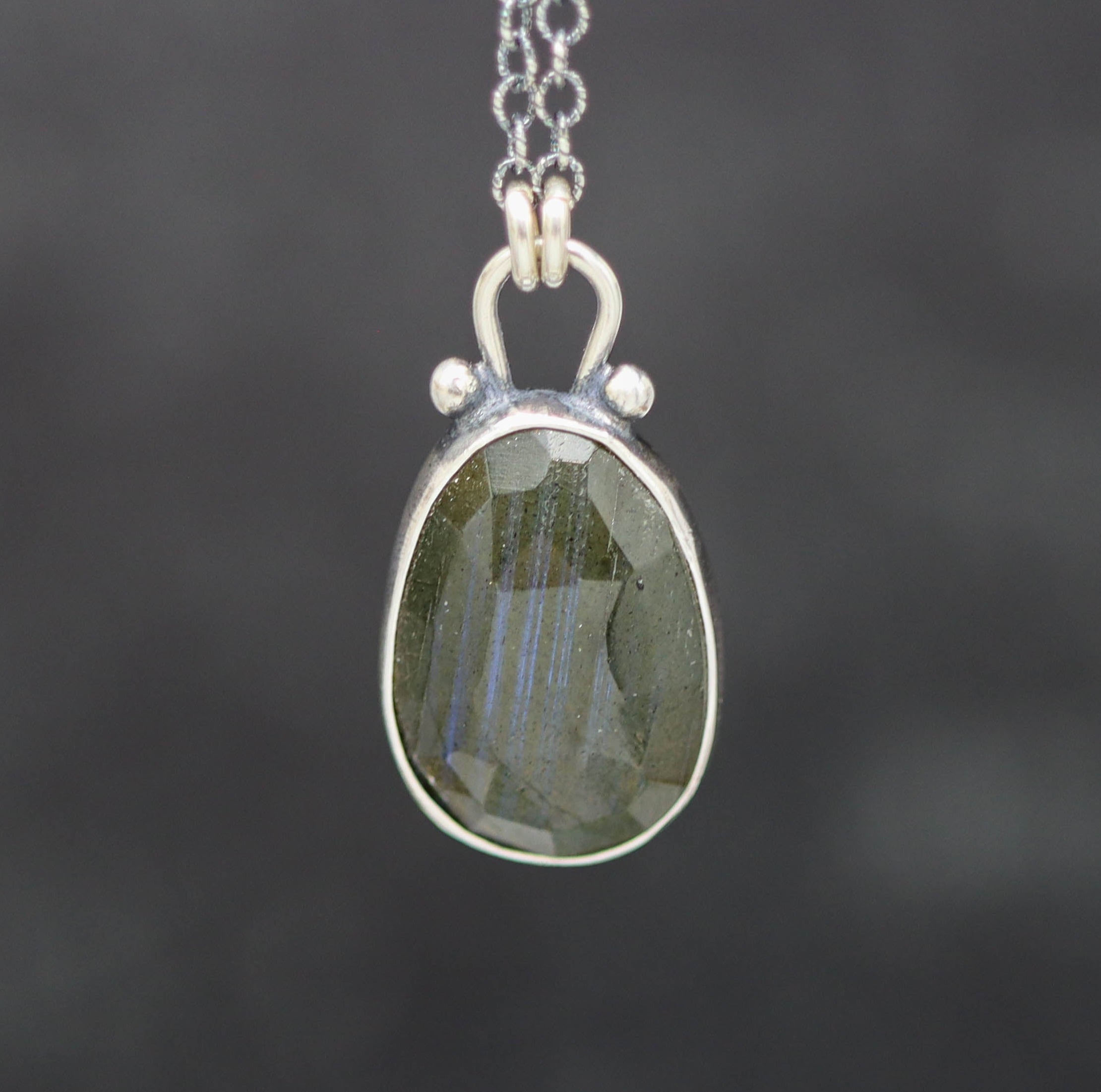 labradorite pendant and silver setting on a dark background