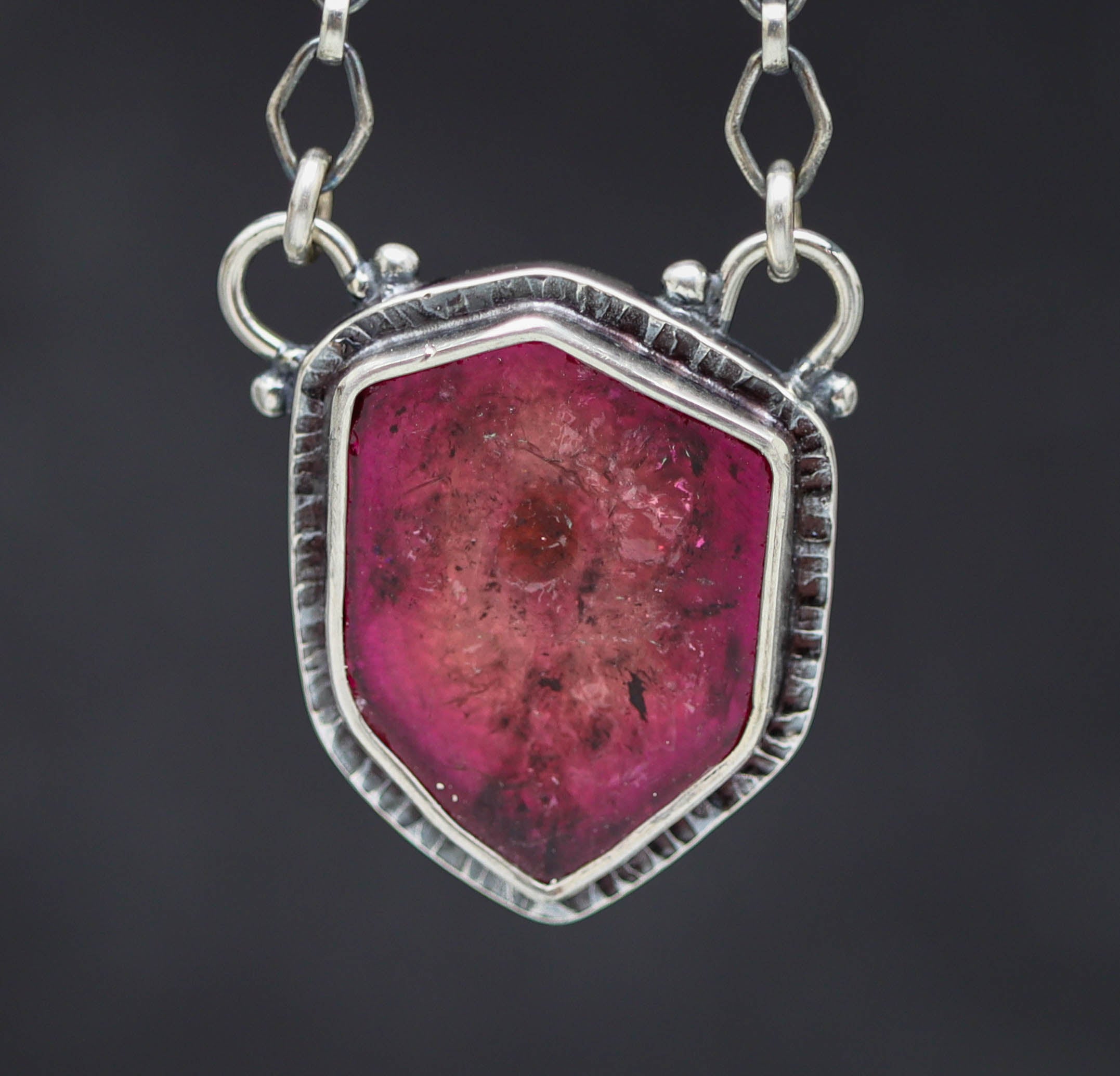 Silver pendant with a pink tourmaline on a dark background
