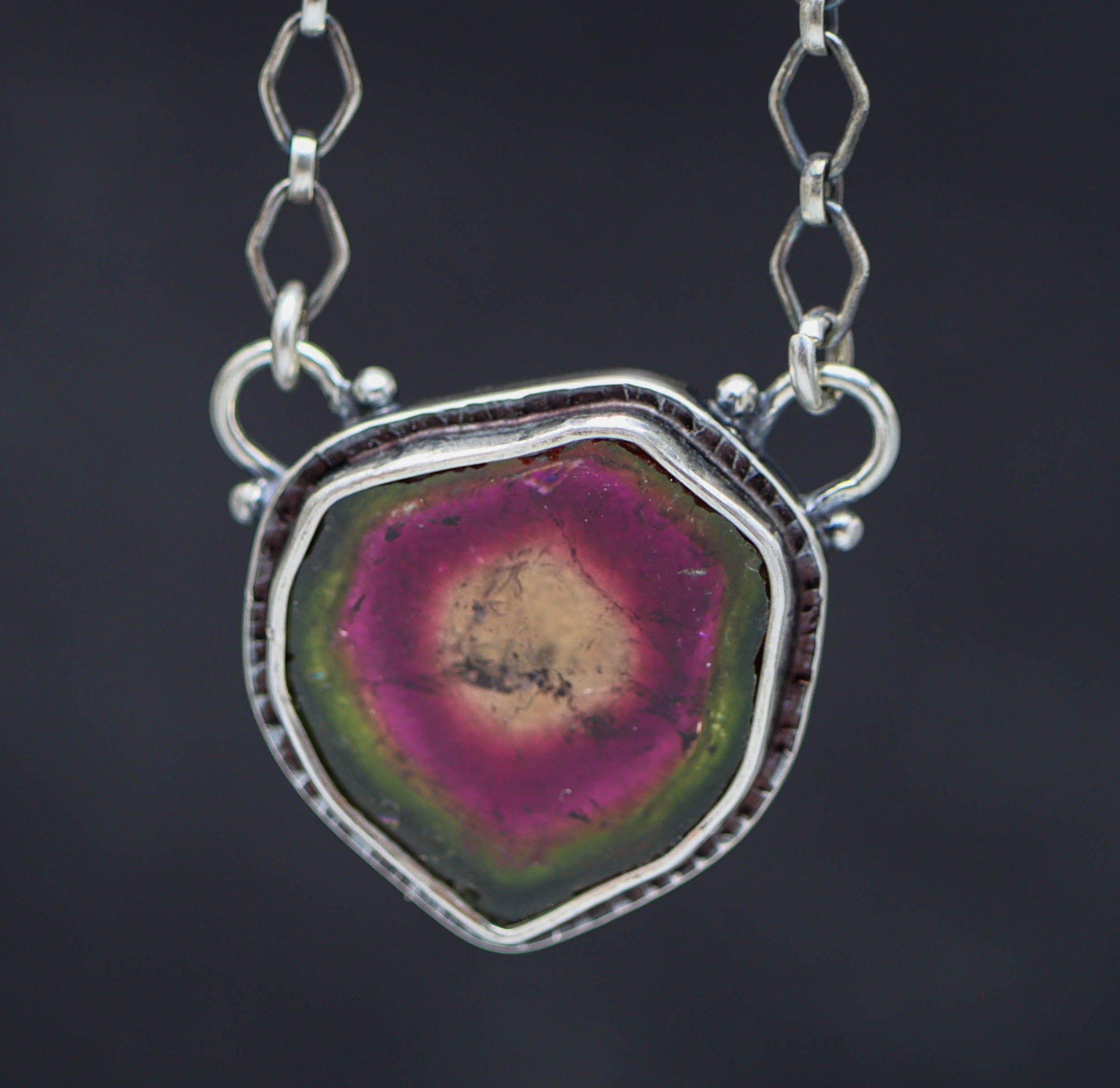 Necklace with a watermelon tourmaline pendant on a dark background