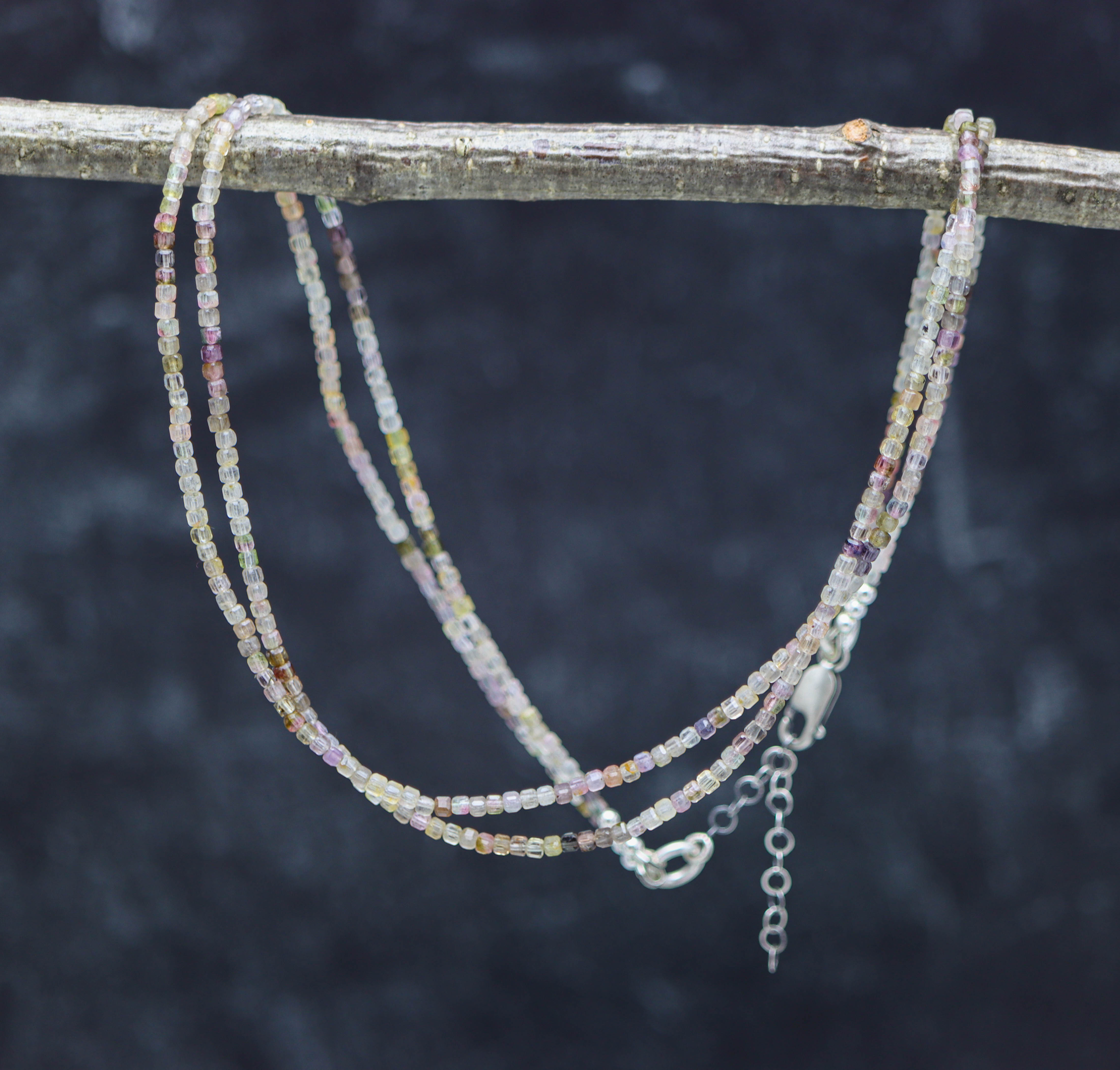 Beaded necklace on a branch with a dark background