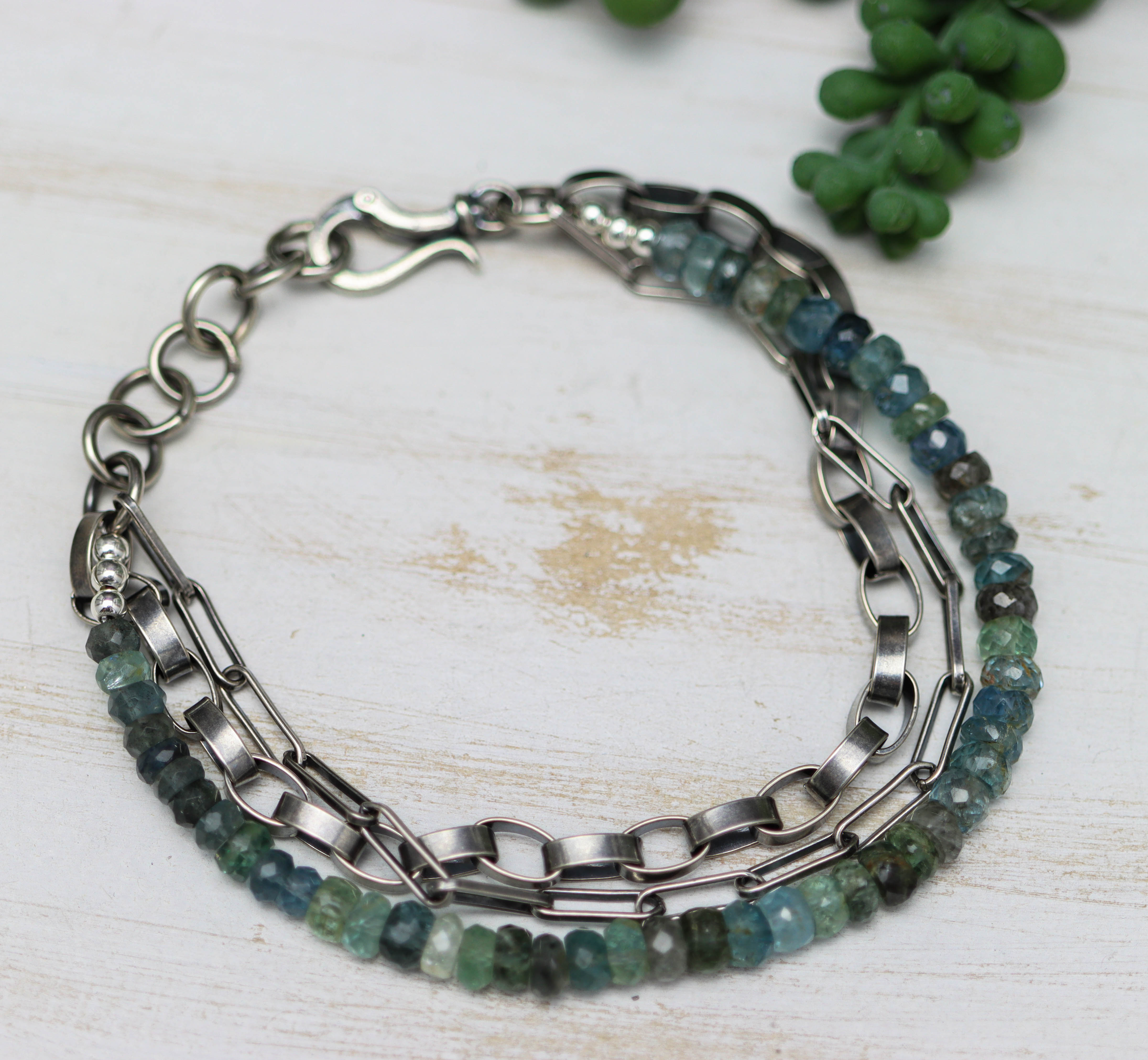Bracelet with green beads and silver chain on a light wooden surface