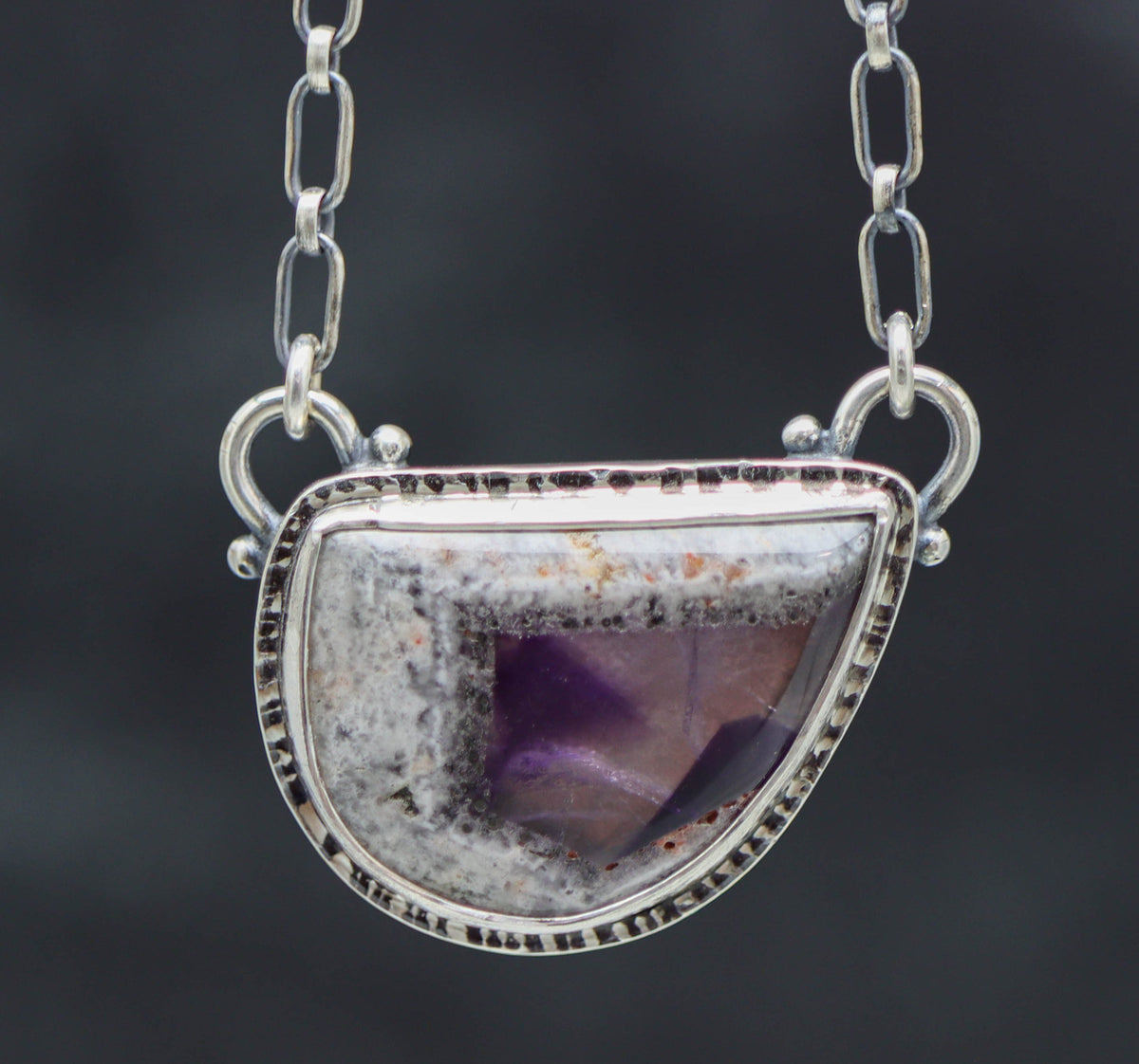 Silver necklace with a semi-precious stone pendant on a dark background