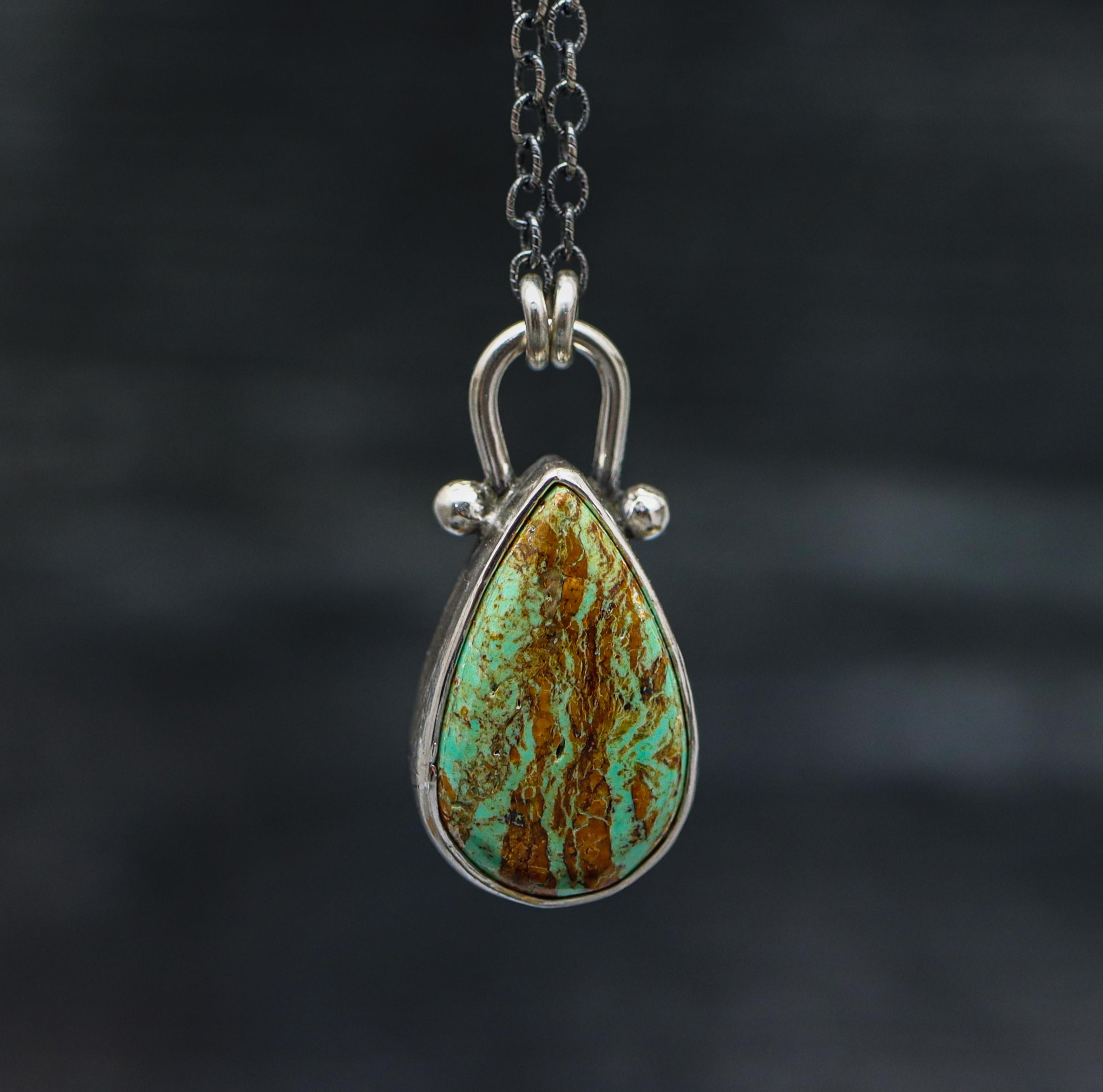 A sterling silver pendant necklace with a Kingman turquoise gemstone set in a silver setting, suspended from a silver chain.