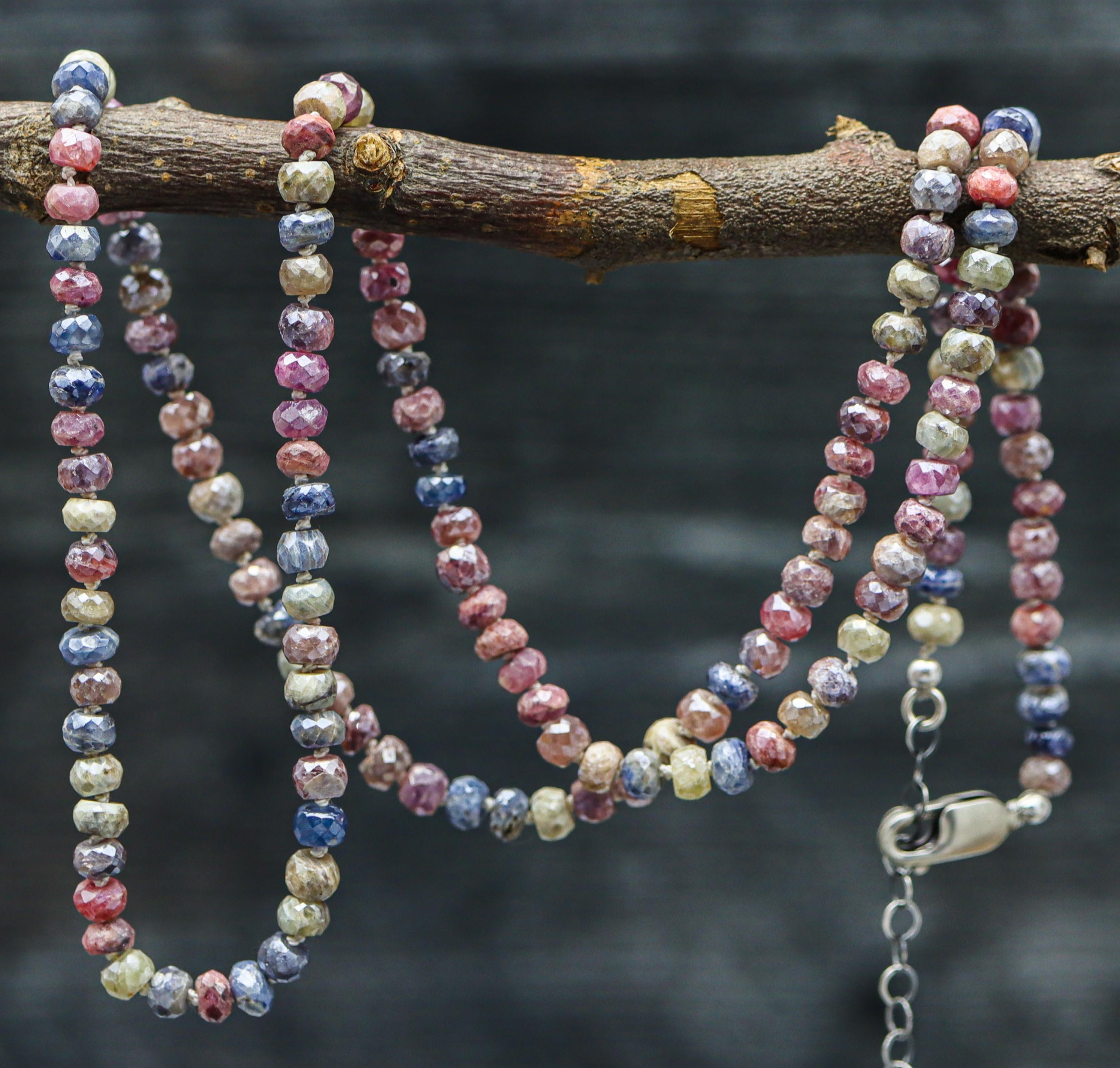 A hand knotted bead necklace featuring multi-colored sapphire beads with a sterling silver closure.