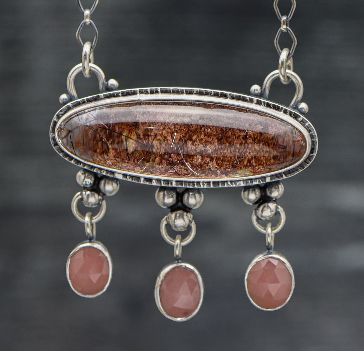A sterling silver pendant featuring a garden quartz gemstone with three guava quartz dangles below, set on a diamond link chain.