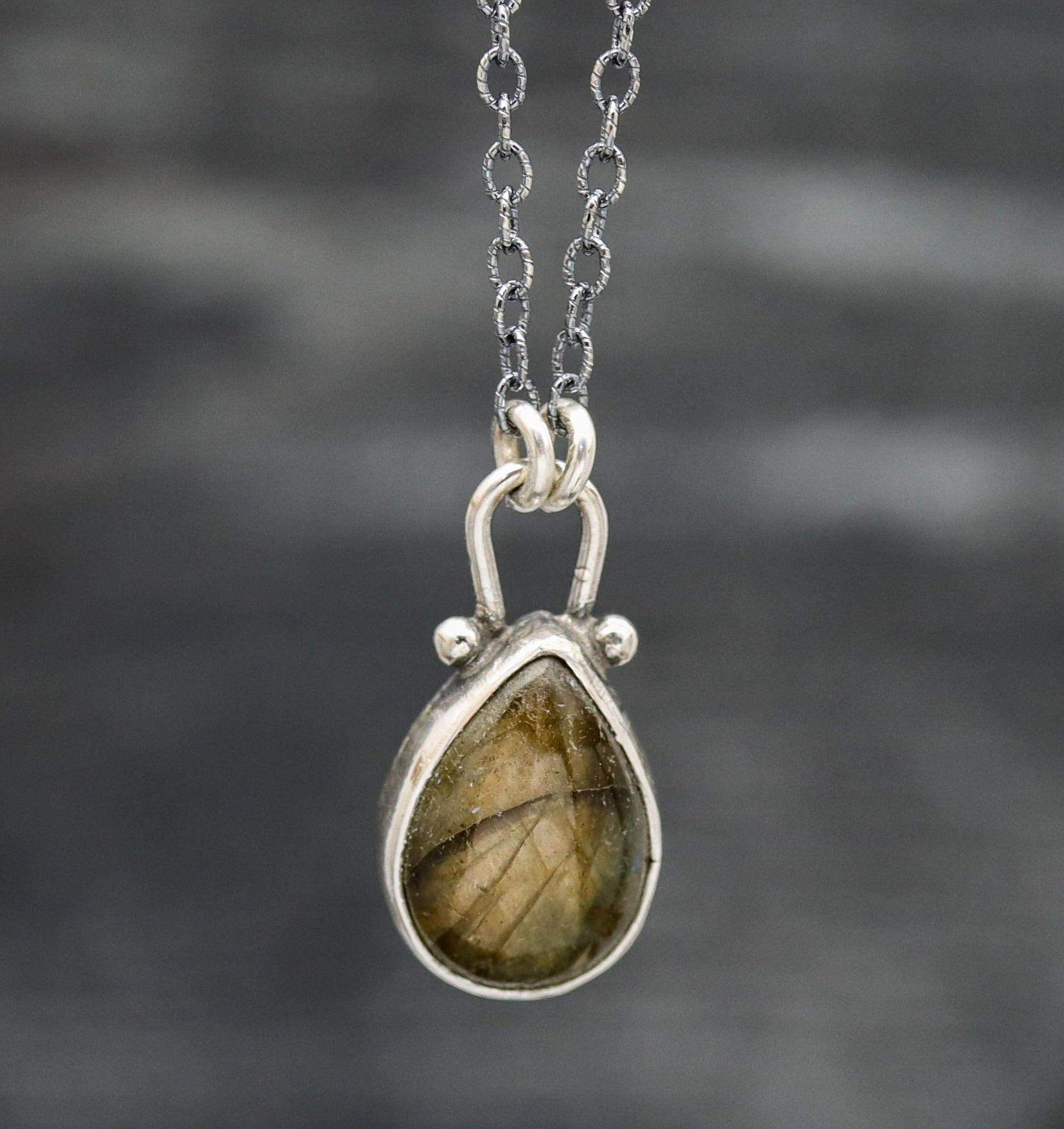 A sterling silver pendant necklace with a labradorite gemstone centerpiece, suspended from an oxidized cable link chain with a lobster claw closure.