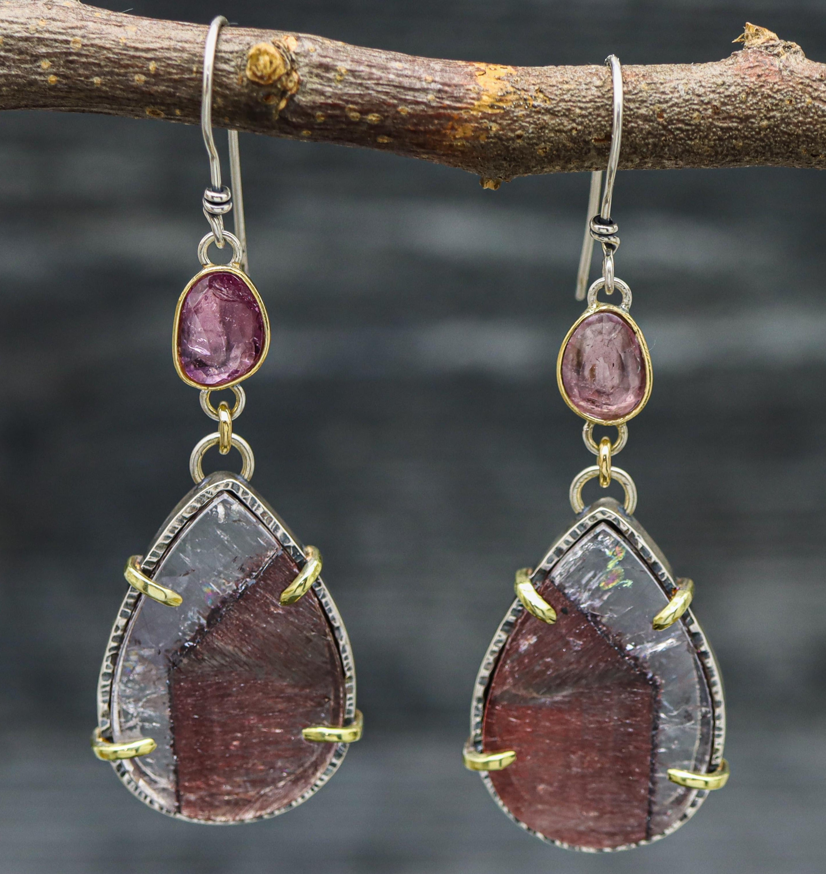 A pair of dangle earrings featuring teardrop-shaped super seven quartz with rose cut pink tourmaline accents, set in sterling silver and 18k gold.