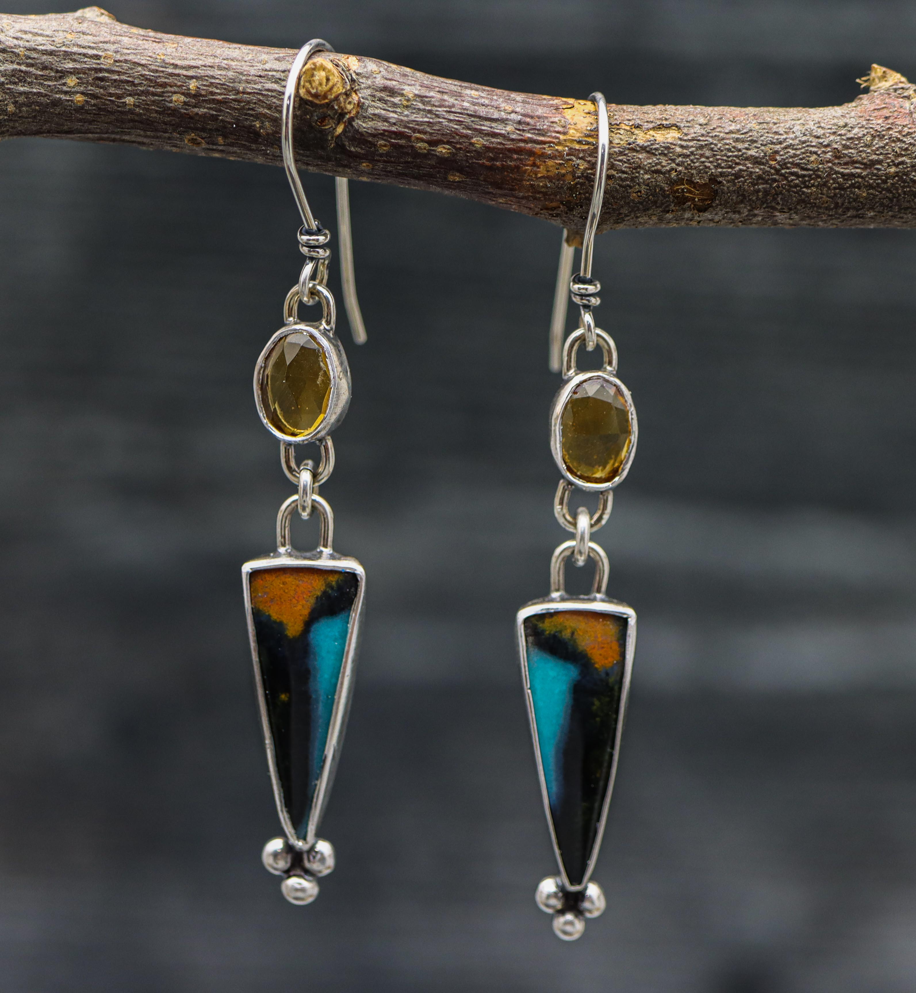 A pair of sterling silver dangle earrings with chrysocolla and mandarine citrine stones, displayed on a branch.