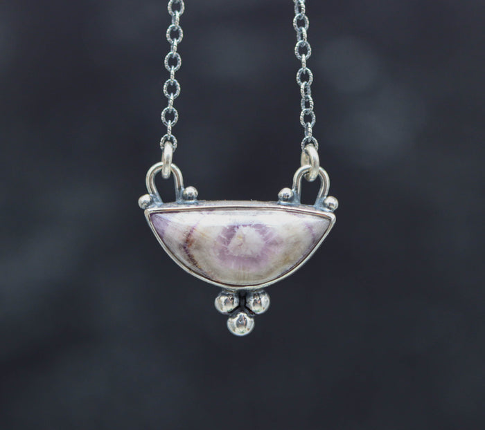 Silver necklace with a unique pendant on a dark background