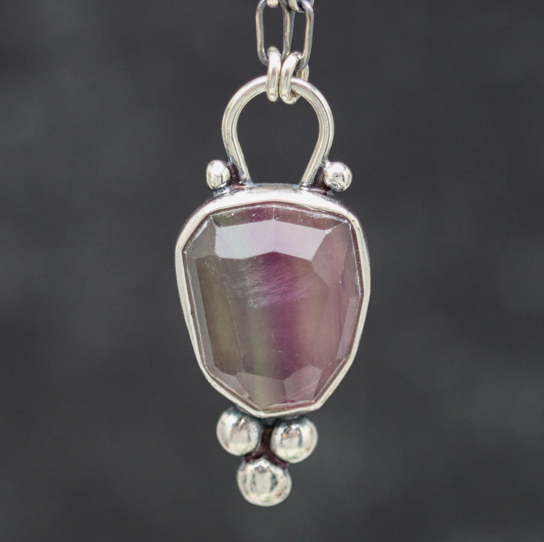 Silver pendant with a pink stone on a dark background