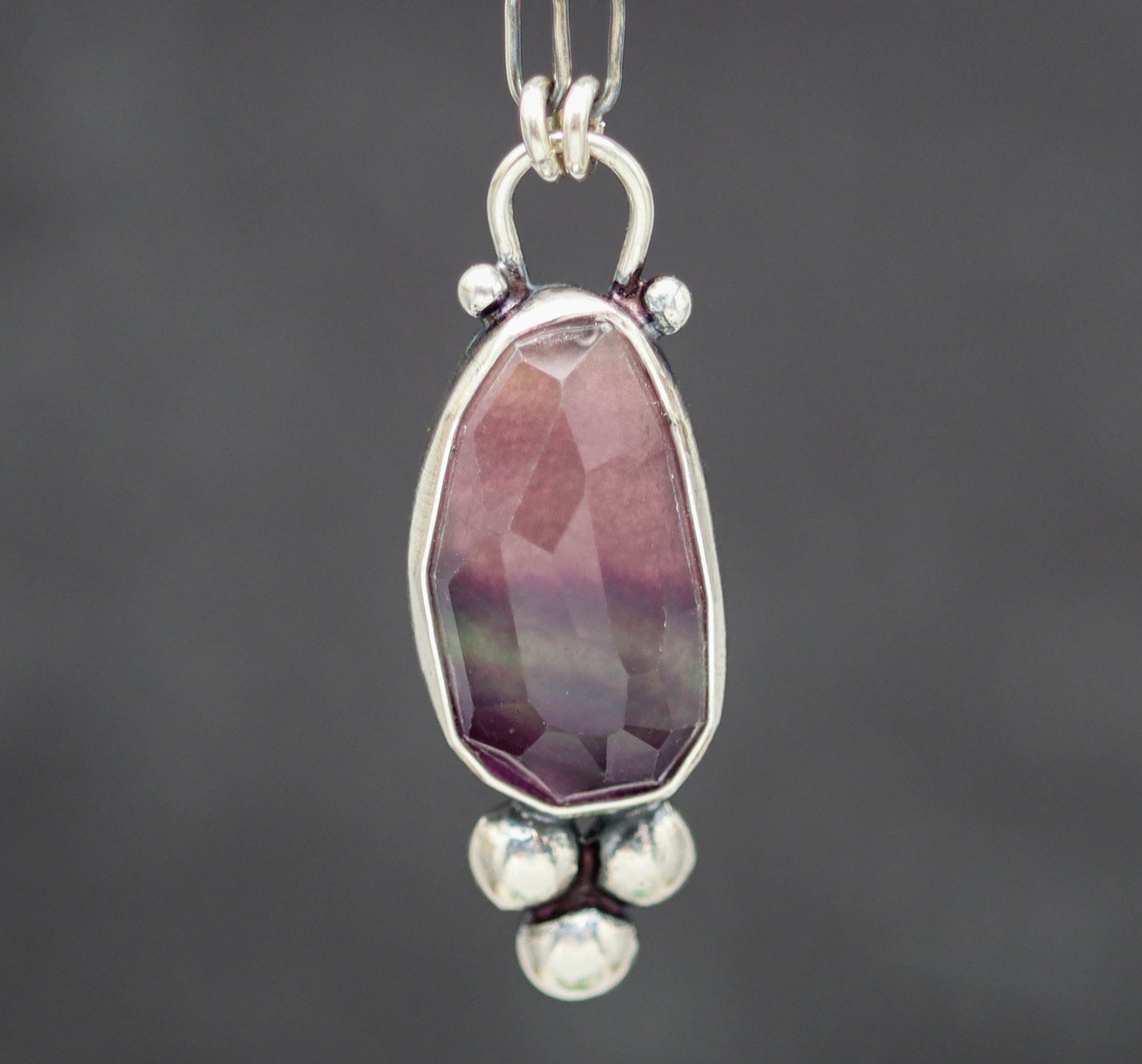 Necklace with a pendant featuring a purple gemstone on a dark background