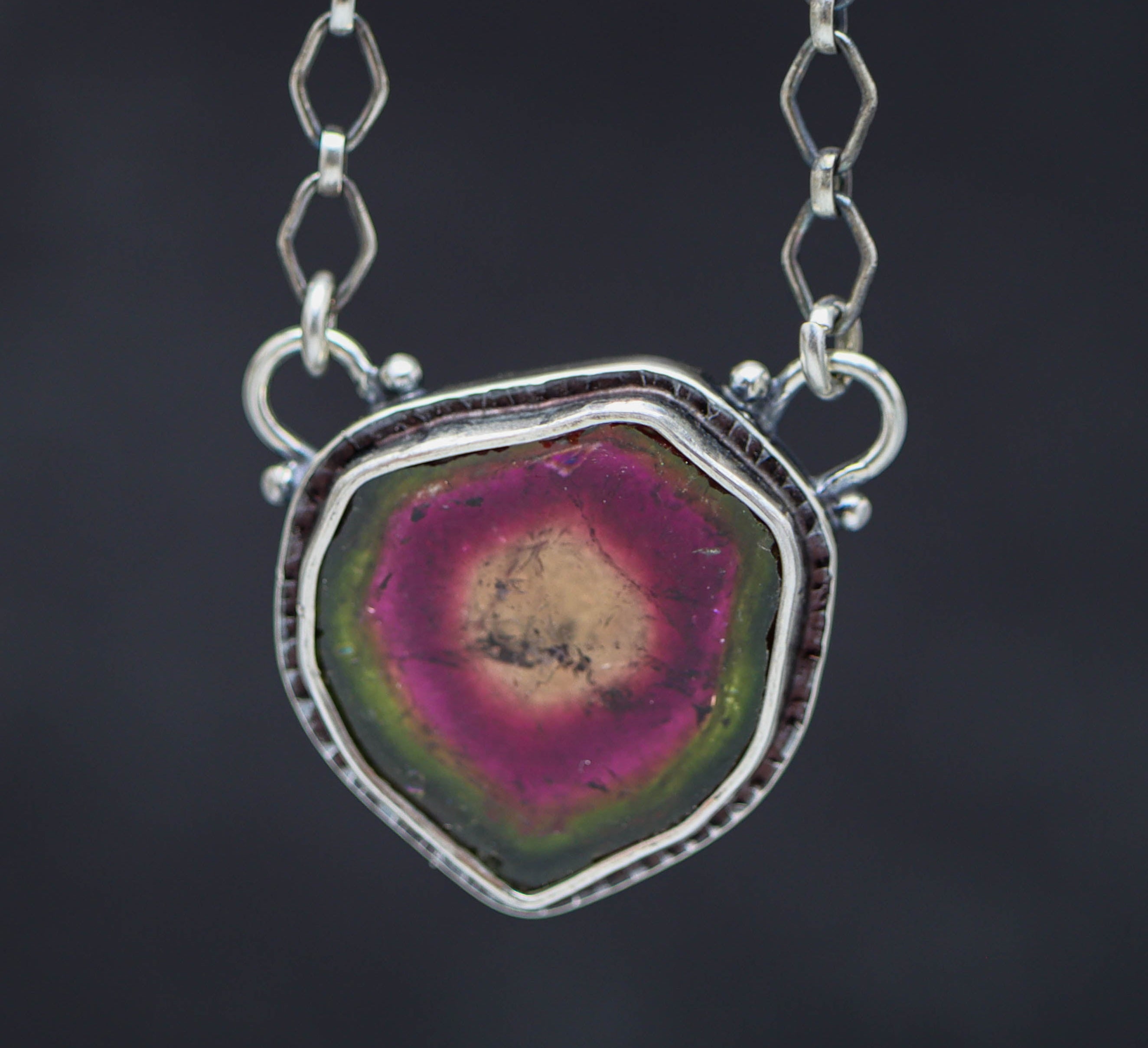 Necklace with a watermelon tourmaline pendant on a dark background