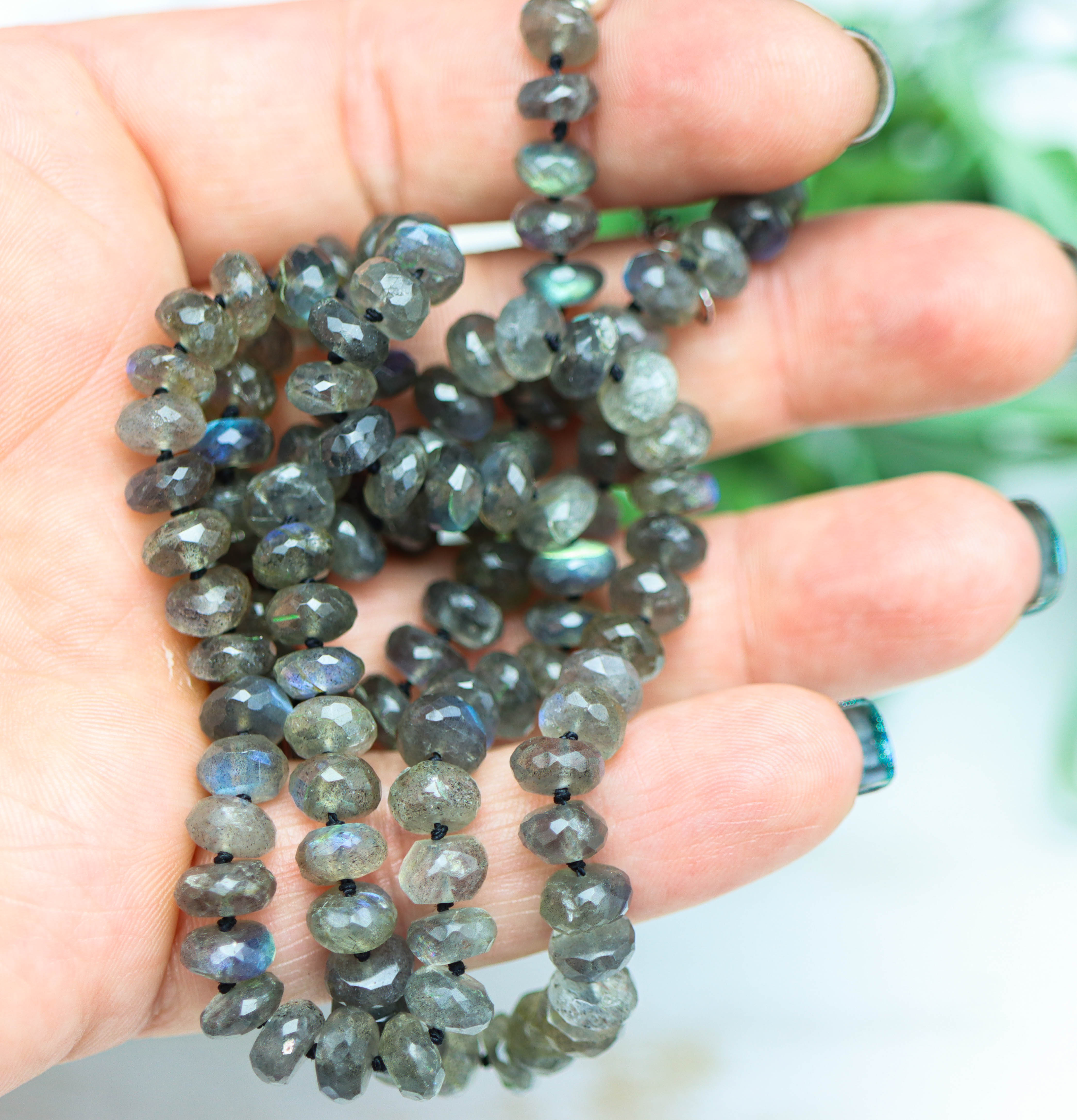 Necklace with faceted gemstones held in a hand against a blurred natural background