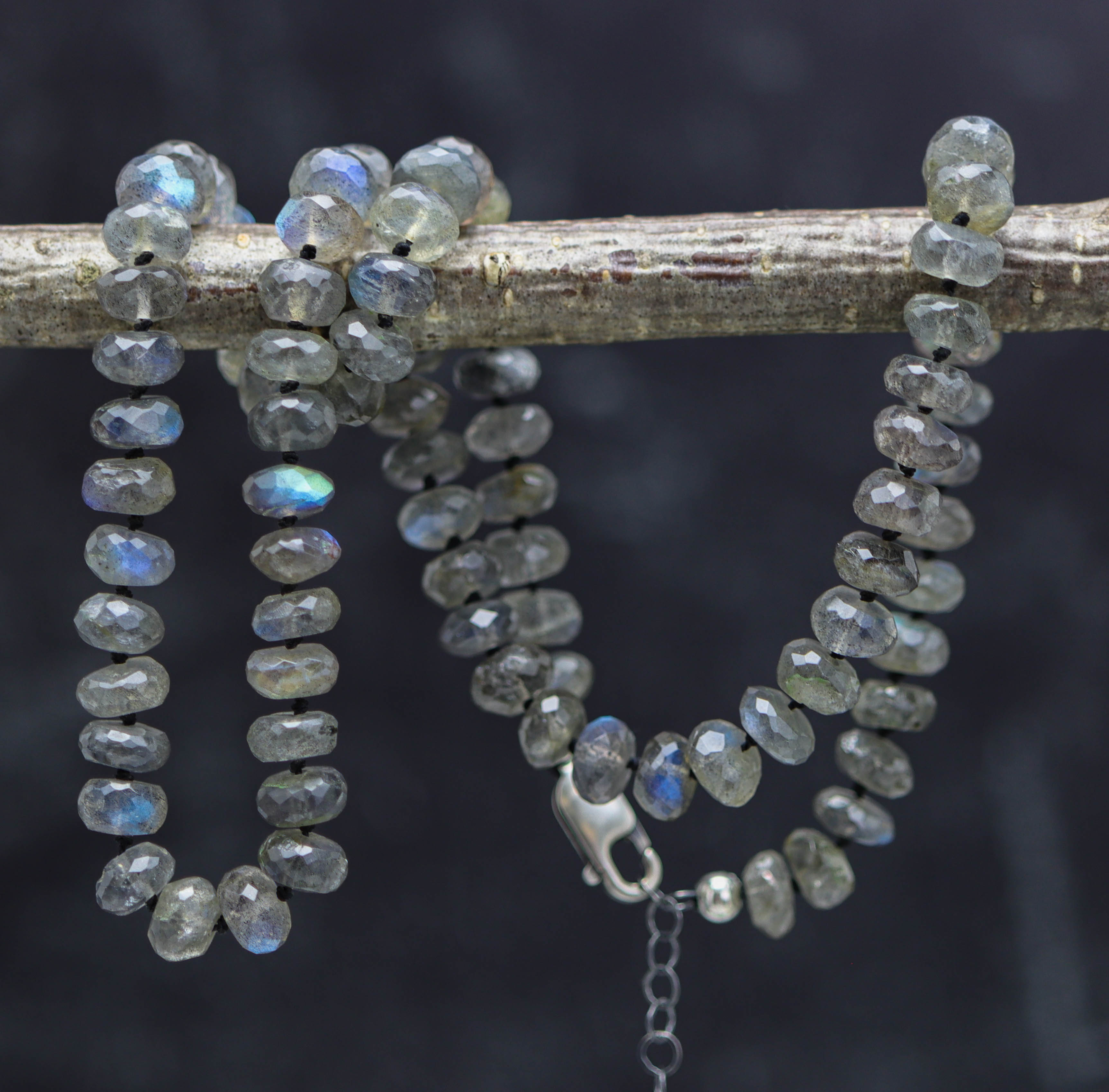 Necklace with faceted gemstones on a branch against a dark background