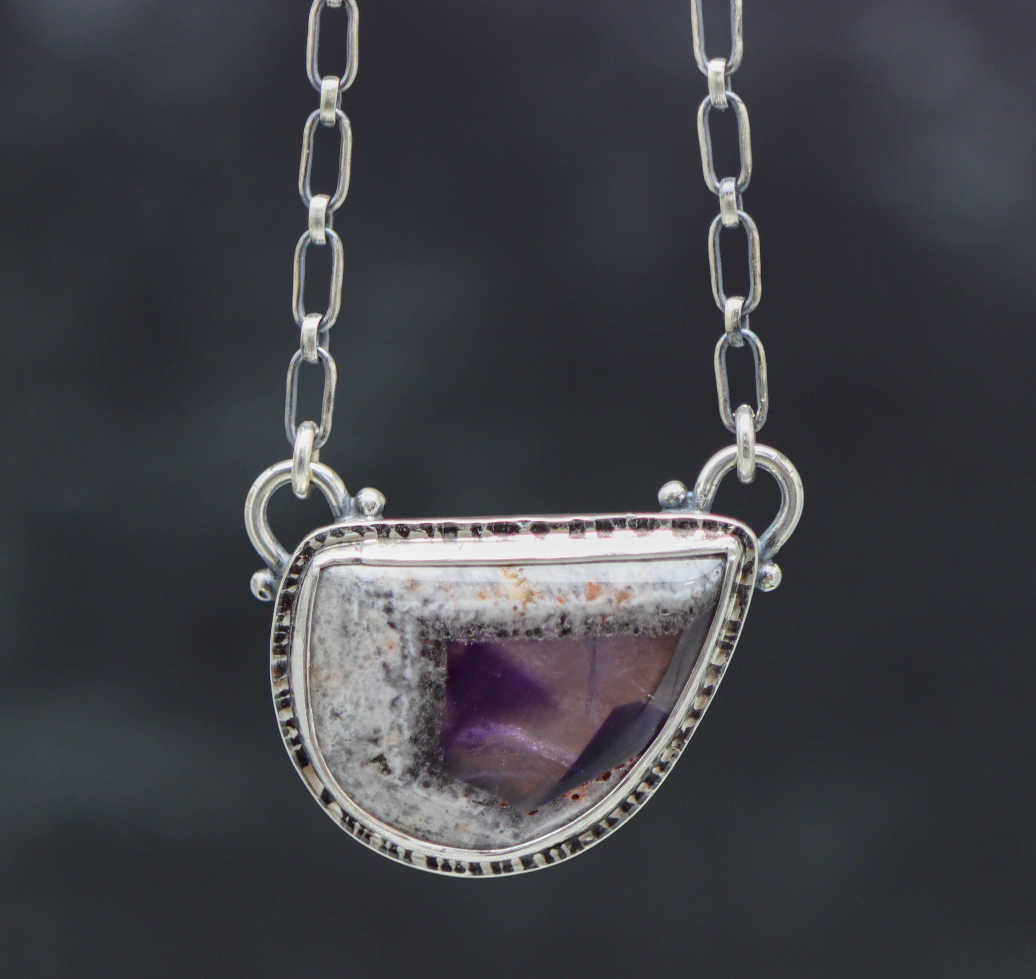 Silver necklace with a semi-precious stone pendant on a dark background