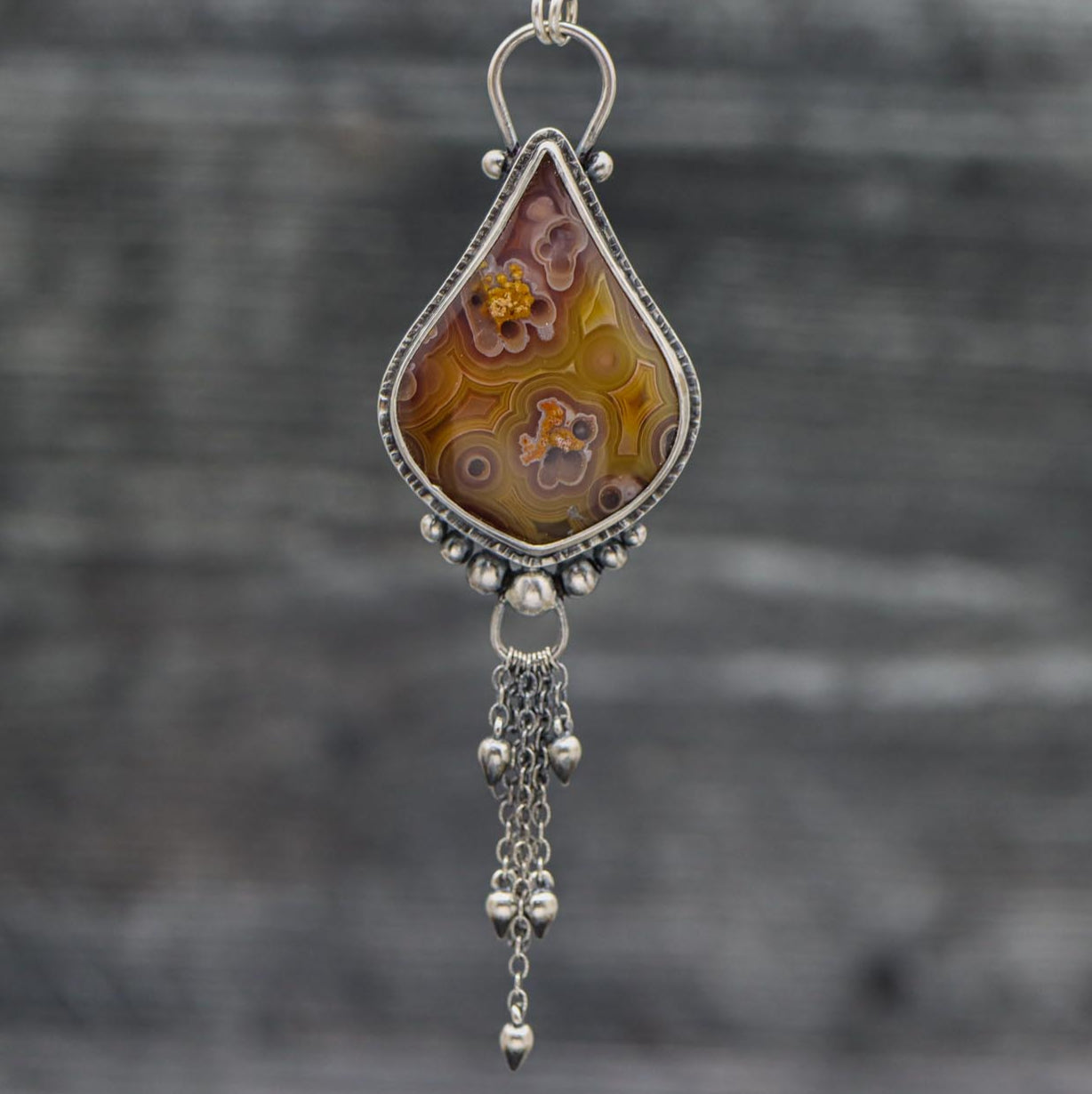 A sterling silver necklace featuring a laguna agate gemstone with a silver chain and dangles.