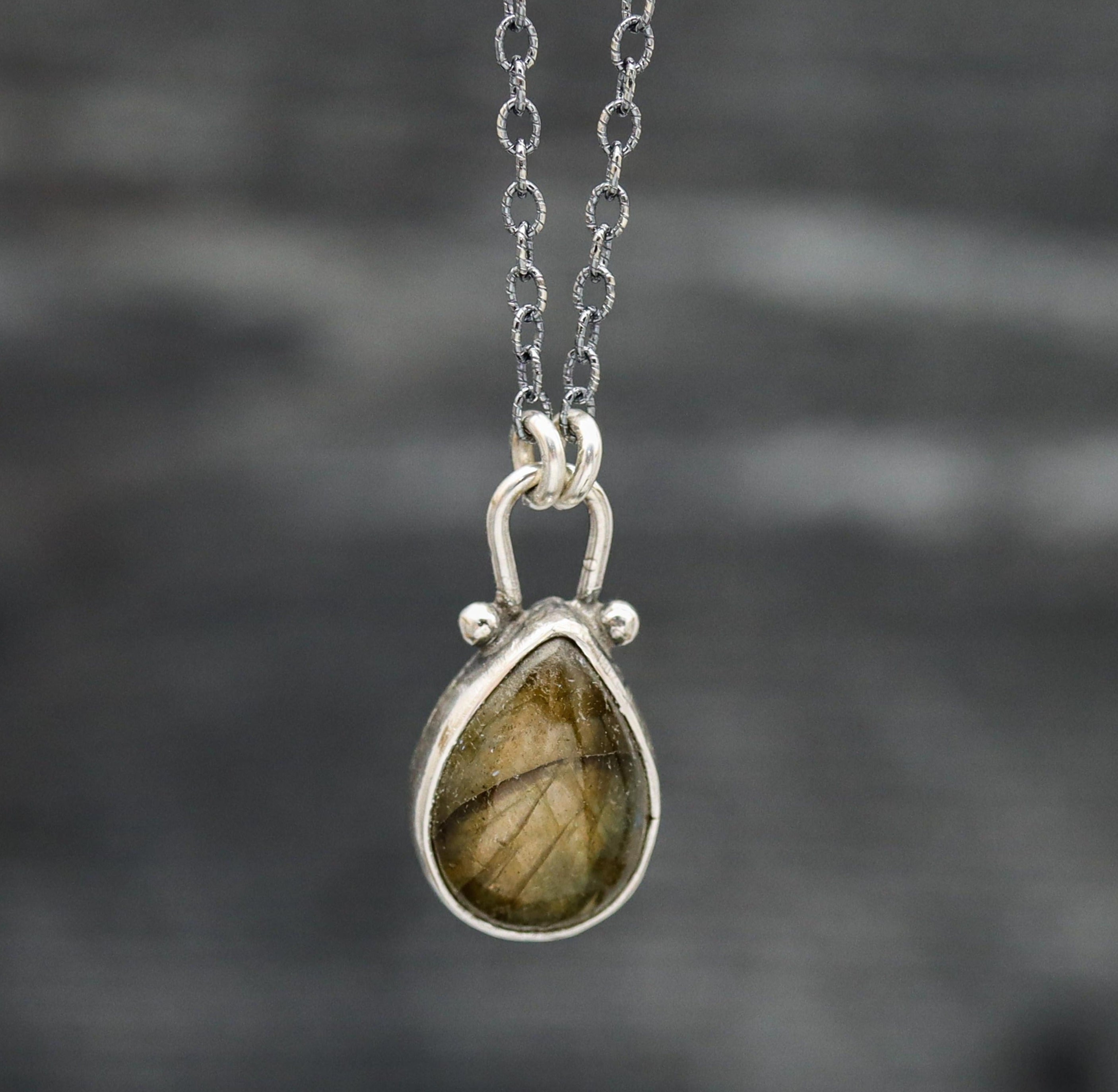 A sterling silver pendant necklace with a labradorite gemstone centerpiece, suspended from an oxidized cable link chain with a lobster claw closure.